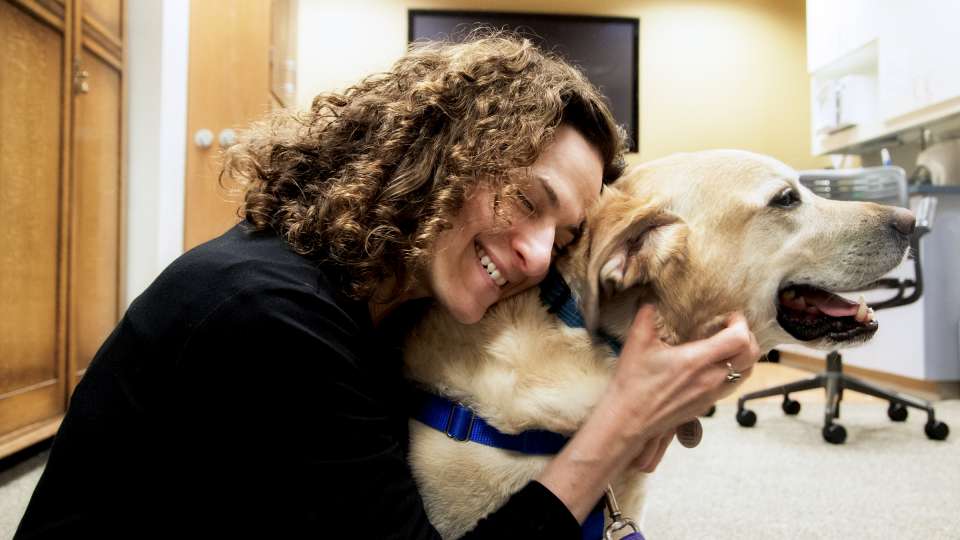 A woman hugs a dog during a pet therapy session.