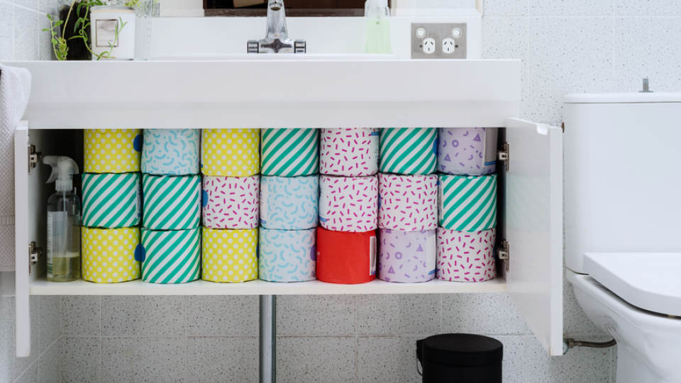 An image of an open bathroom cabinet that contains multiple rolls of toilet paper