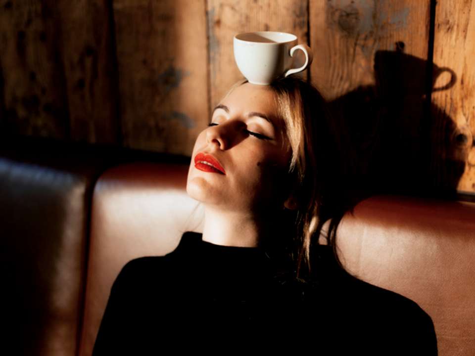 A woman with a coffee cup balanced on her head.