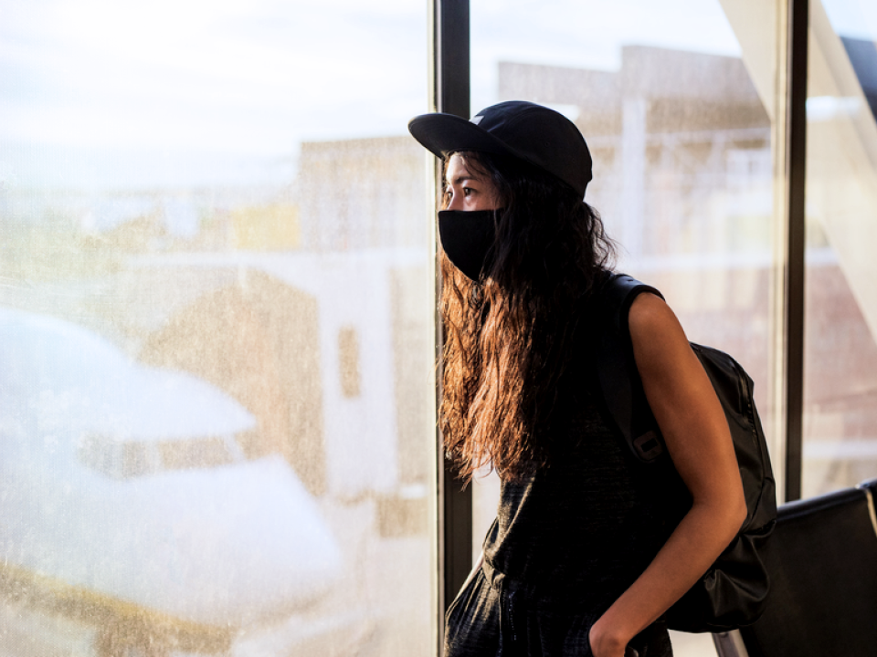 woman at an airport wearing a protective mask