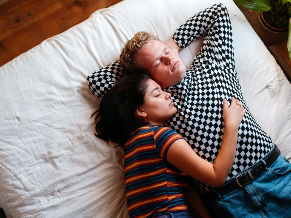 A photo of a couple napping together in bed