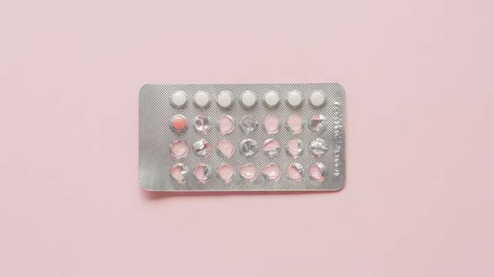 a birth control blister package with one pill left, over a pink background