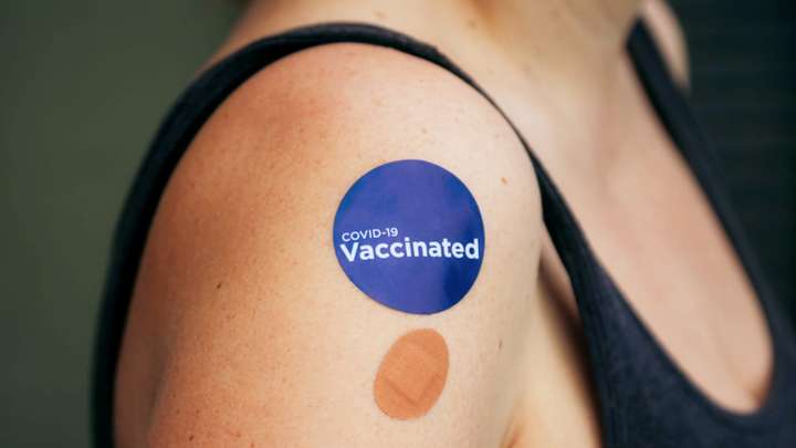 Woman arm with bandage and vaccinated sticker