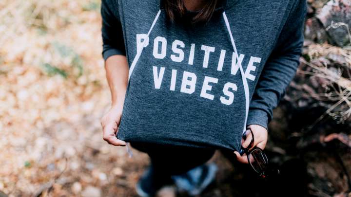 A person wears a sweatshirt that says 'positive vibes.'
