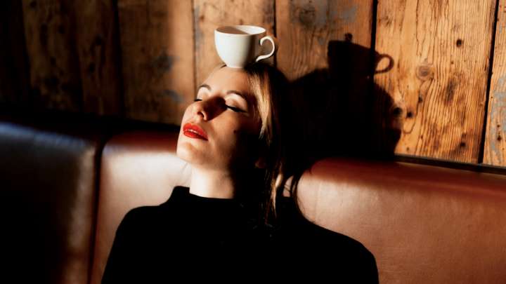 A woman with a coffee cup balanced on her head.