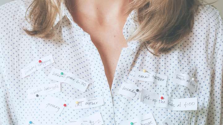 busy woman with the many tasks she needs to do pinned to her shirt