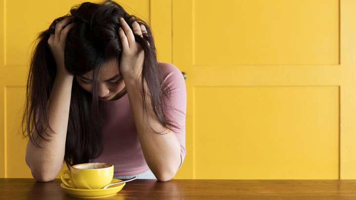 woman with head in her hands because she's over-caffeinated 
