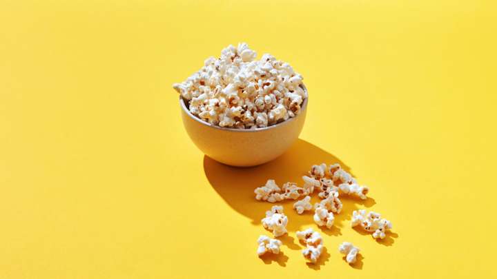 A bowl of popcorn on a yellow background.