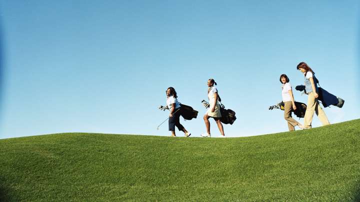 Four women walking on a golf course