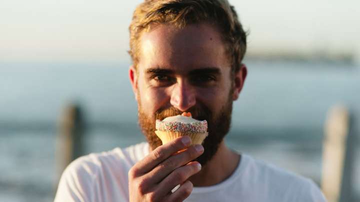 man by the water holding a cupcake