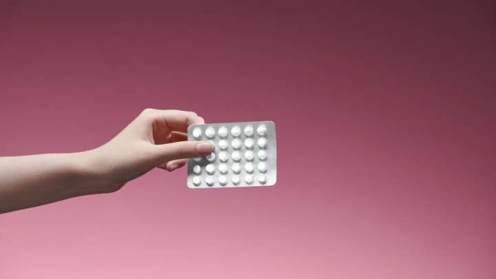 A photo of a hand holding birth control pills
