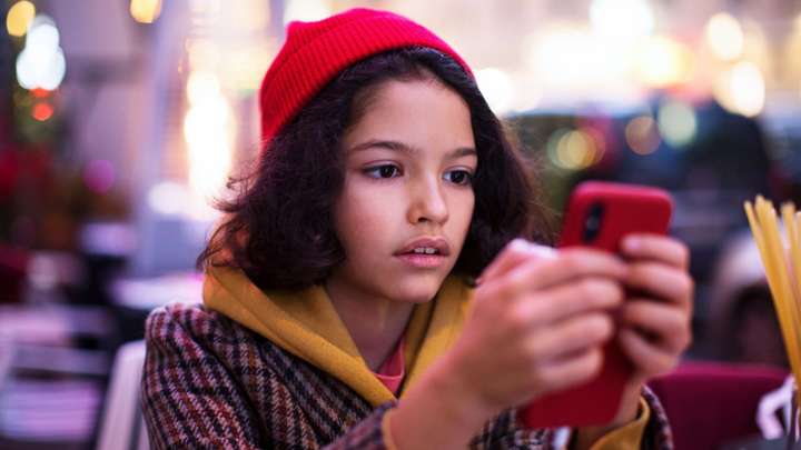 girl in red hat looking at her phone