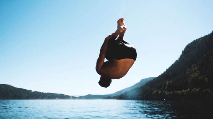 Man back-flipping into a lake 