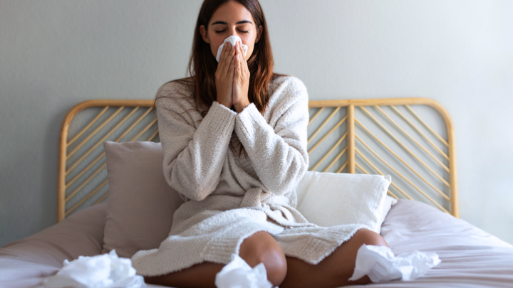 A photo of a woman on her bed with a cold