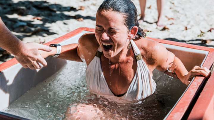 A woman does a cold plunge in a tub filled with ice.