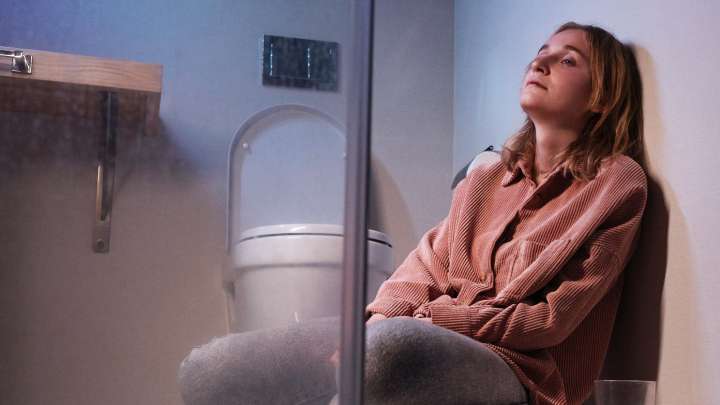 Woman sitting on bathroom floor next to toilet 