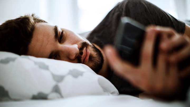 Man lying in bed looking at phone