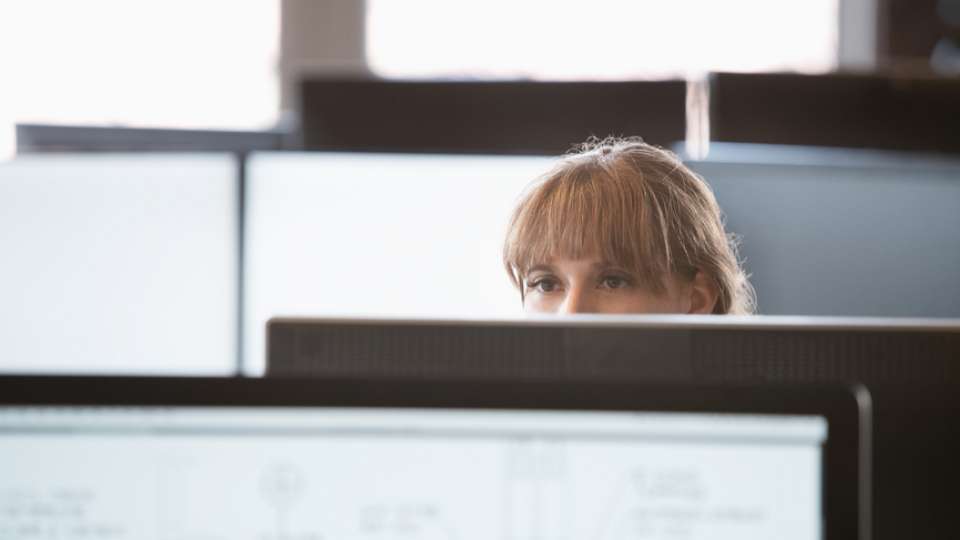 Woman staring over office cube wall