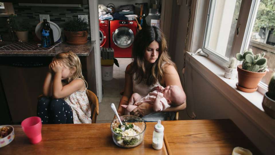 Exhausted mama holds baby at the kitchen table