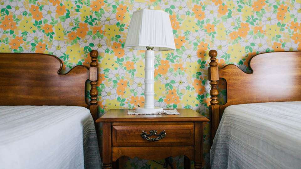Twin beds against wall with vintage wallpaper