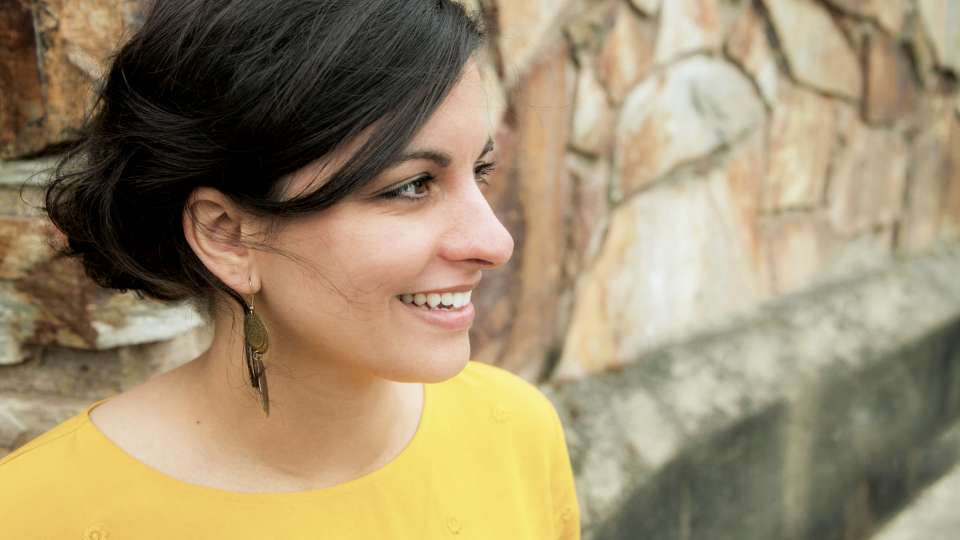 A woman in a yellow shirt standing in front of a wall