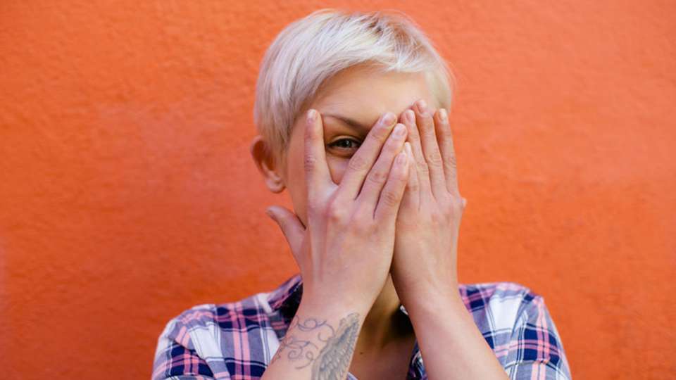 Blonde woman covering one eye with her hands