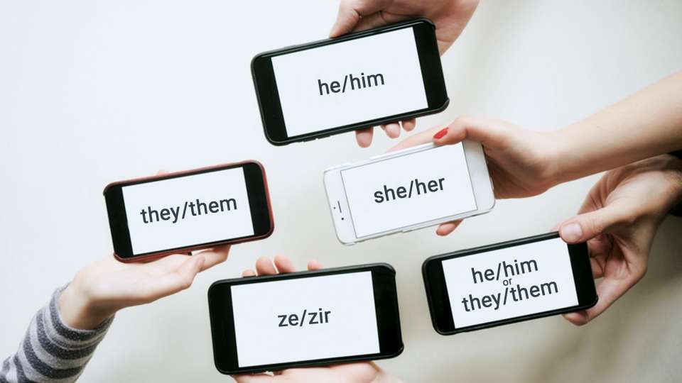 Hands hold phones that show different pronouns on the screens.