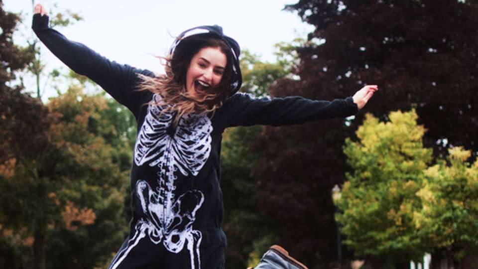 Woman in skeleton costume jumps in the air