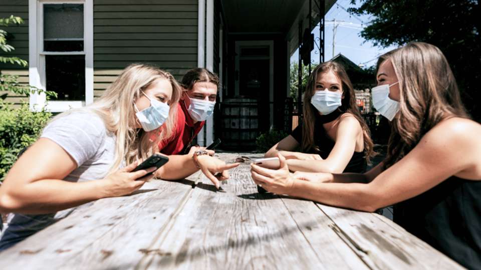 Friends around picnic table with masks on