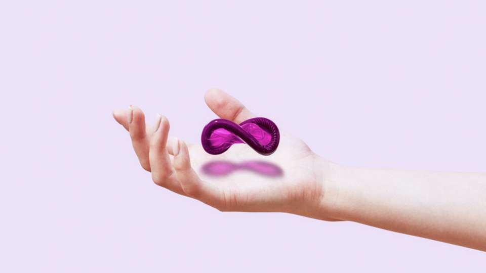 A purple condom in the shape of an infinity symbol floats above a woman's outstretched hand.