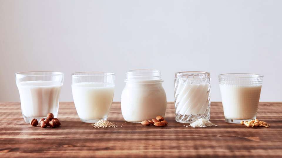 A lineup of non-dairy milk alternatives in glasses.