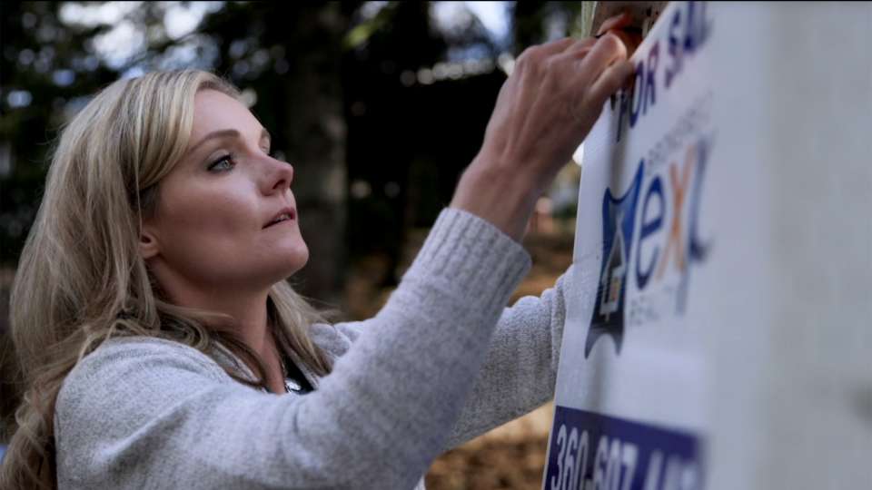 Melissa Hunter hangs a real estate sign.