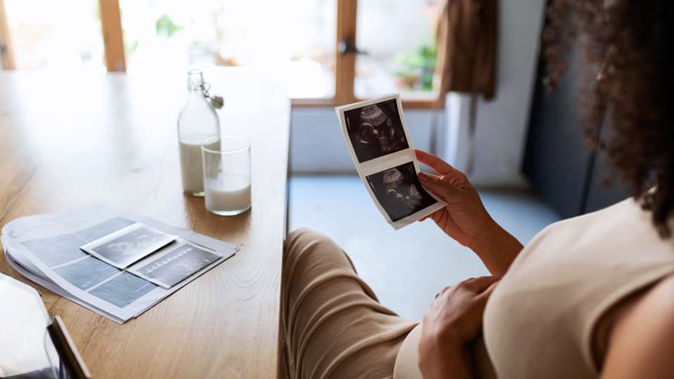 A pregnant woman looks at photos of her ultrasound.