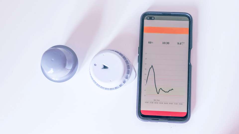 A closeup of a continuous glucose monitor and phone app.