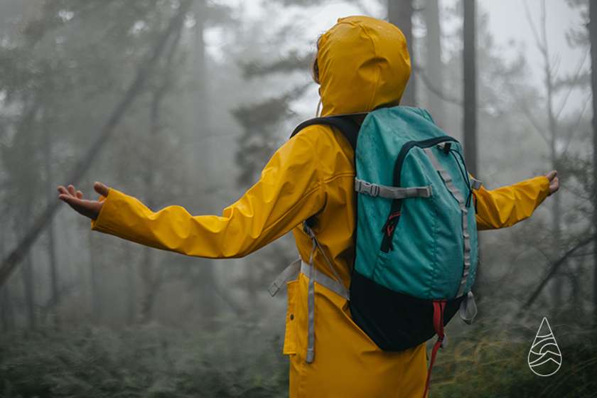 A person in a yellow rain coat with arms raised.