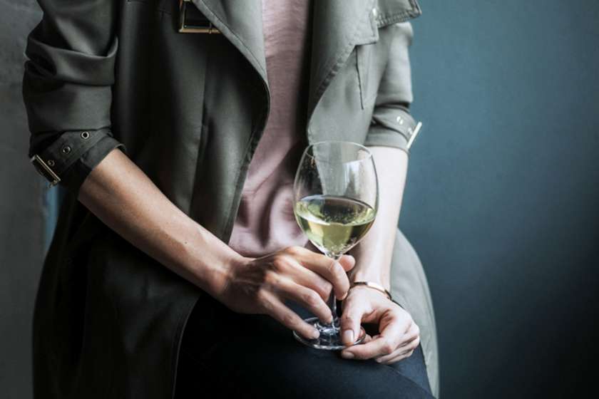An anonymous woman holds a glass of wine.