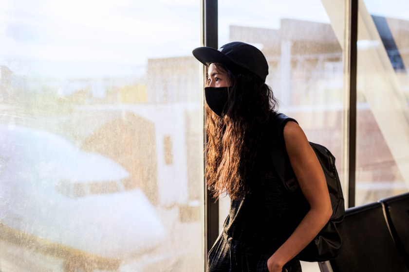 woman at an airport wearing a protective mask
