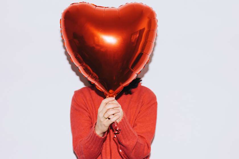 Woman holding heart balloon in front of her face