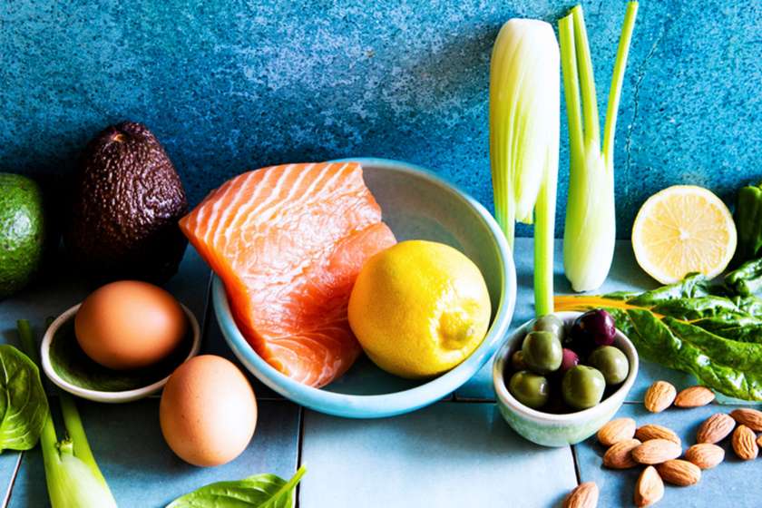 salmon, lemon and other healthy foods against blue background