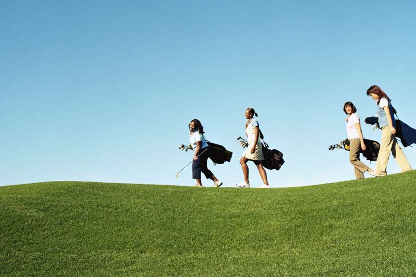 Four women walking on a golf course