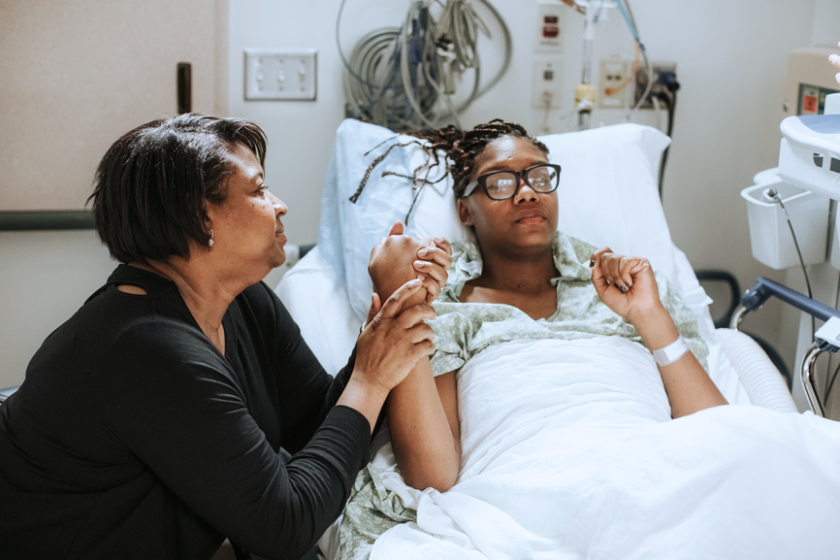 A photo of a mother comforting her daughter in the hospital