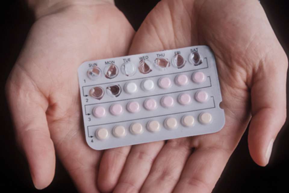 women's hands holding combined hormonal birth control pills