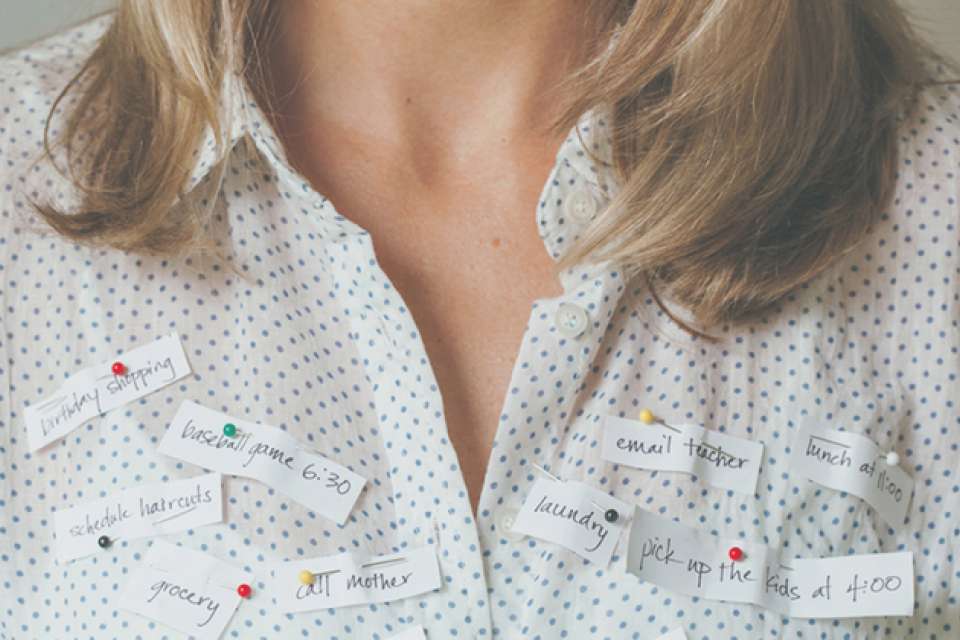 a woman's chest with to-do list items pinned to her shirt