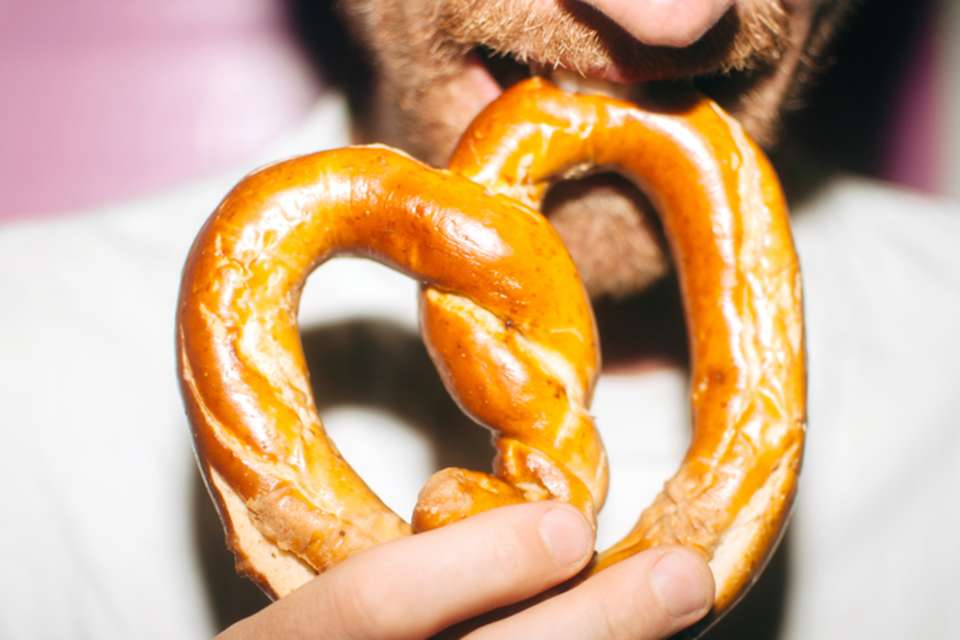 a man eating a large soft pretzel