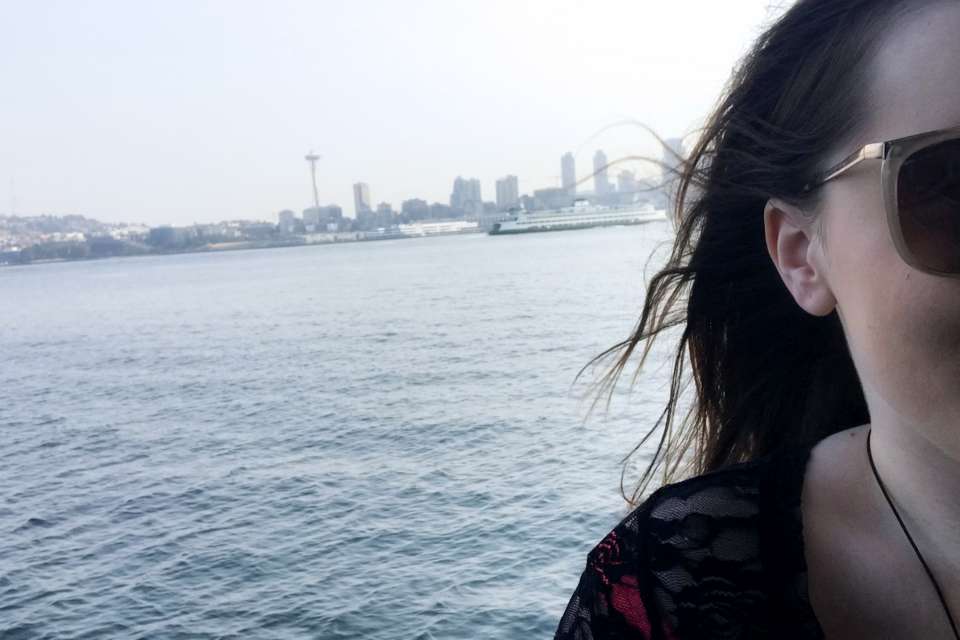 A woman in front of water and the Seattle skyline.