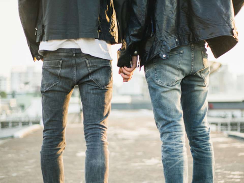 A couple of millennials holding hands wearing jeans and leather jackets