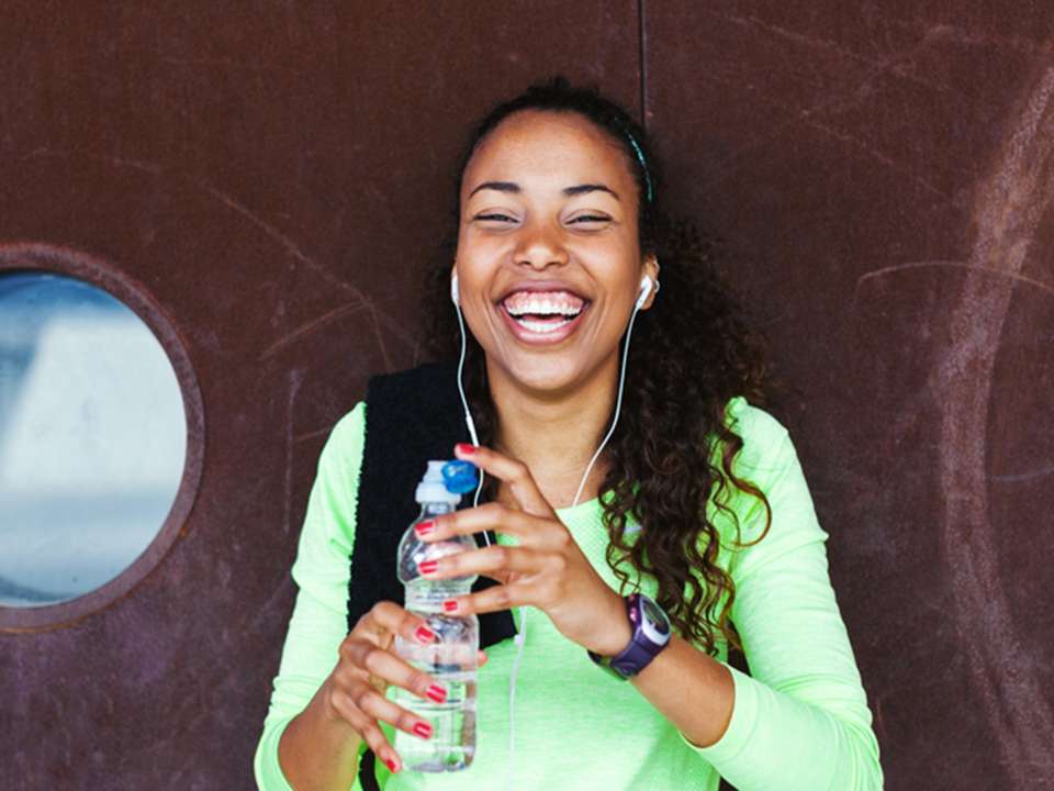 a young woman holding a water bottle and smiling