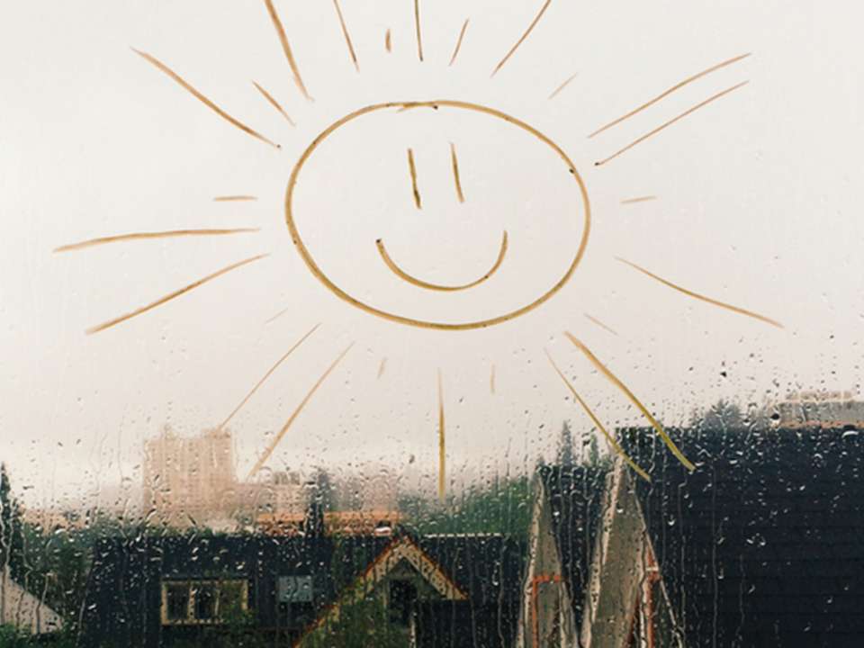 child's sunshine drawing on a rain covered window