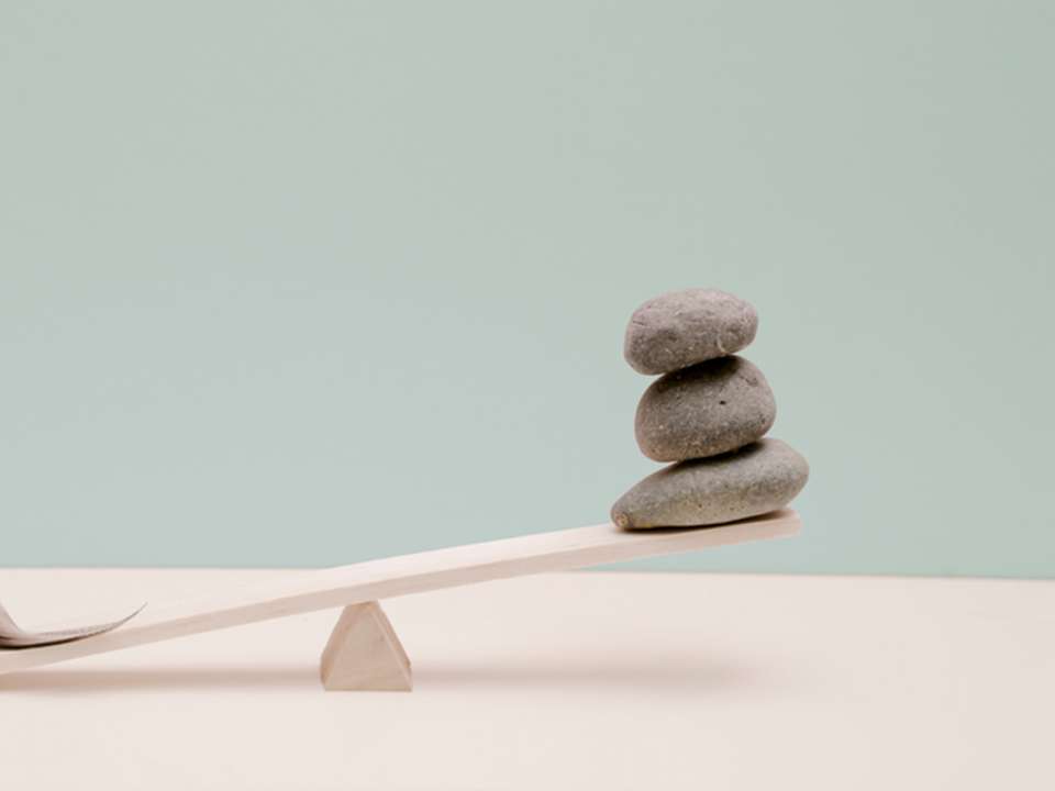 an unbalanced scale with a feather and rocks on it