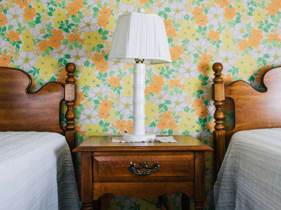 Twin beds against wall with vintage wallpaper